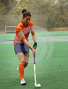 Female hockey player exercising on a grass field