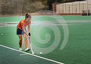 Female hockey player exercising on a grass field