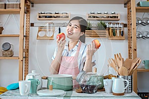 Female holding an apple in the kitchen. Portrait of a pretty woman holding apple healthy food in the kitchen. Happy woman which