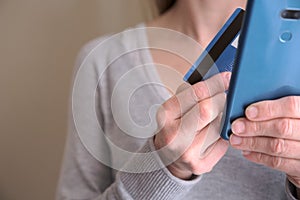 Female holding credit card while using her smart phone for inputting card information and making payment