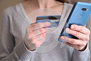 Female holding credit card while using her smart phone for inputting card information and making payment