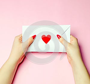 Female holding an envelope with a red heart. Valentines day concept. A love letter to the beloved. Greeting valentine card.
