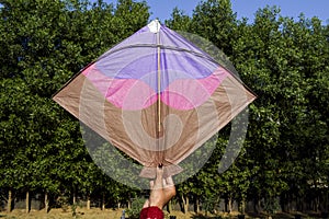 Female holding and flying a big kite with nature background on occasion of Indian kite flying festival of Makar sankranti or