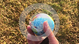 Female holding global earth in her hand, against yellow grass, ecology concept, human impact, save the planet