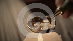 Female holding golden spoon with liquid. Close up shot of woman warms wax in a golden old spoon on a candle for sealing