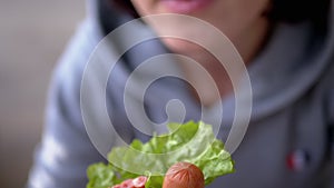 Female Holding in Hands a bitten Juicy American Hot Dog with Sausages in Diner