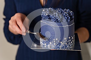 Female holding a homemade cake. Close up of female hand showing cake.