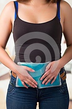 Female holding ice gel pack on her belly , medical concept, in office background