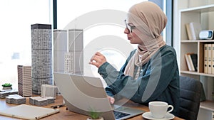 Female holding model while typing on computer indoors