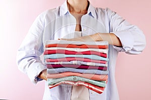 Female holding a pile of folded clothes, unisex for both man & woman, different color & material. Trip preparation concept.