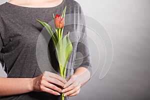 Female holding red flower.