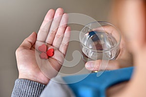 Female is holding red pills in heart shape.