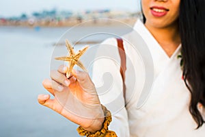 Female holding a starfish on the beach