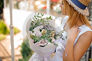 Female holds a bouquet of roses, eucalyptus and succulents