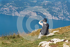 female Holidaymaker on the top of Monte Baldo on Lake Garda near Malcesine takes a photo of the landscape