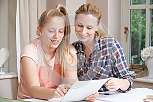 Female Home Tutor Helping Girl With Studies Using Digital Tablet photo