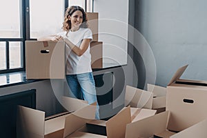 Female homeowner standing with cardboard boxes on day of relocation to new home. Moving and delivery