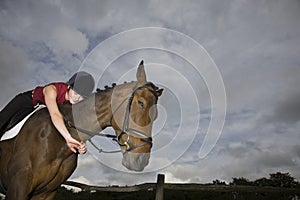 Female horseback rider embracing horse