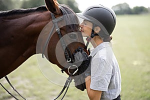 Female horseman hugging head of Thoroughbred horse