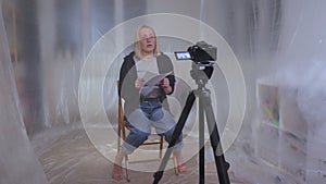 A female hostage sitting on a chair reads a text from a paper to the camera