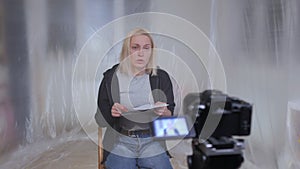 A female hostage sitting on a chair reads a text from a paper to the camera