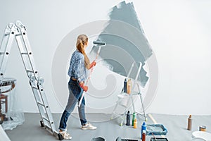 Female house painter paints wall