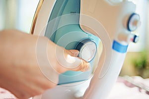 Female in house in sunny day setting ironing temperature