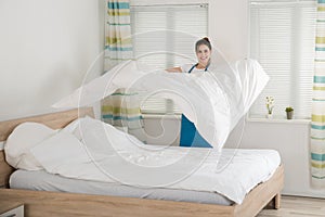 Female Housekeeper Changing Bedsheet On Bed