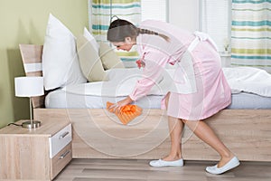 Female Housekeeper Cleaning Bed