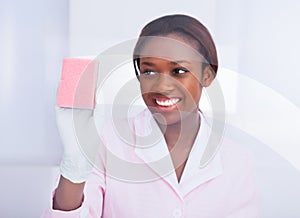 Female housekeeper cleaning glass in hotel