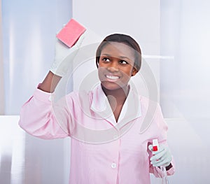 Female housekeeper cleaning glass in hotel