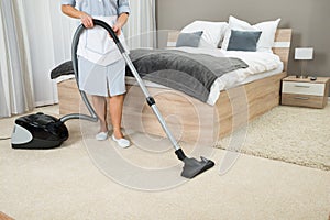 Female housekeeper cleaning with vacuum cleaner