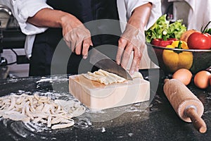 Female housewife making homemade pasta with flour and eggs over