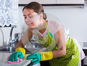 Female houseworker with rag and cleanser indoors