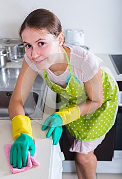 Female houseworker with rag and cleanser indoors
