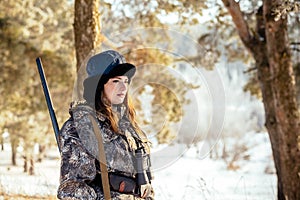 Female hunter in camouflage clothes ready to hunt, holding gun a