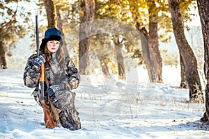 Female hunter in camouflage clothes ready to hunt, holding gun a