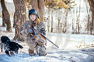 Female hunter in camouflage clothes ready to hunt, holding gun a