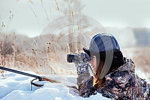 Female hunter in camouflage clothes ready to hunt, holding gun a