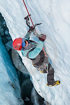 Female ice climber smashing ice tool into glacier ice in Alaska