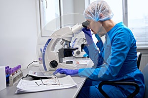 Female immunologist examines biological material under a microscope