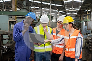 Female industrial engineers have to consult with colleagues while using laptop