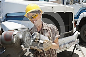 Female industrial worker buffing a truck engine cylinder photo