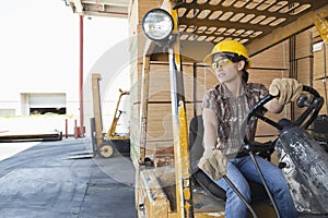 Female industrial worker looking away while driving forklift truck