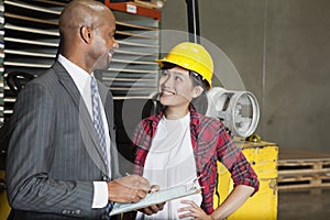 Female industrial worker looking at male inspector as he writes on clipboard