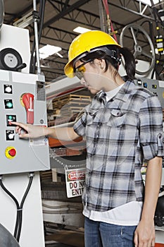 Female industrial worker operating manufacturing machine at factory