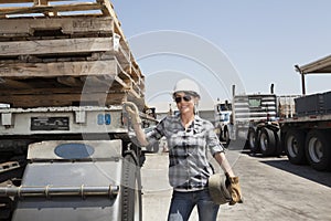 Female industrial worker standing by flatbed truck in timber yard