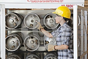 Female industrial worker taking out propane cylinder