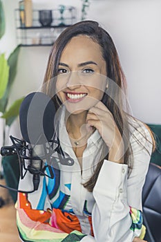 Female influencer recording a podcast for internet using mic in her home studio