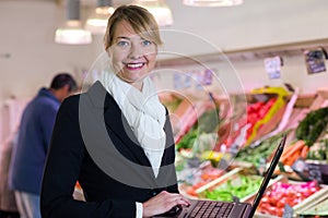 Female inspector in greengrocers holding laptop